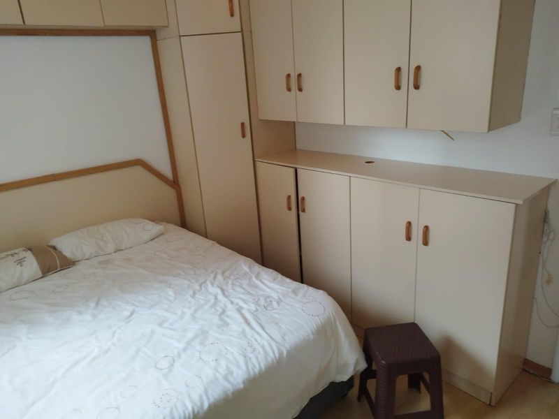 Bedroom featuring extensive built-in cabinetry and light-toned laminate flooring, offering ample storage space within a functional layout.