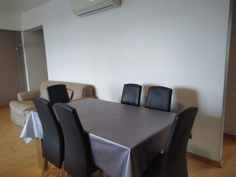 A living and dining area featuring laminate flooring and a wall-mounted split-system air conditioning unit.