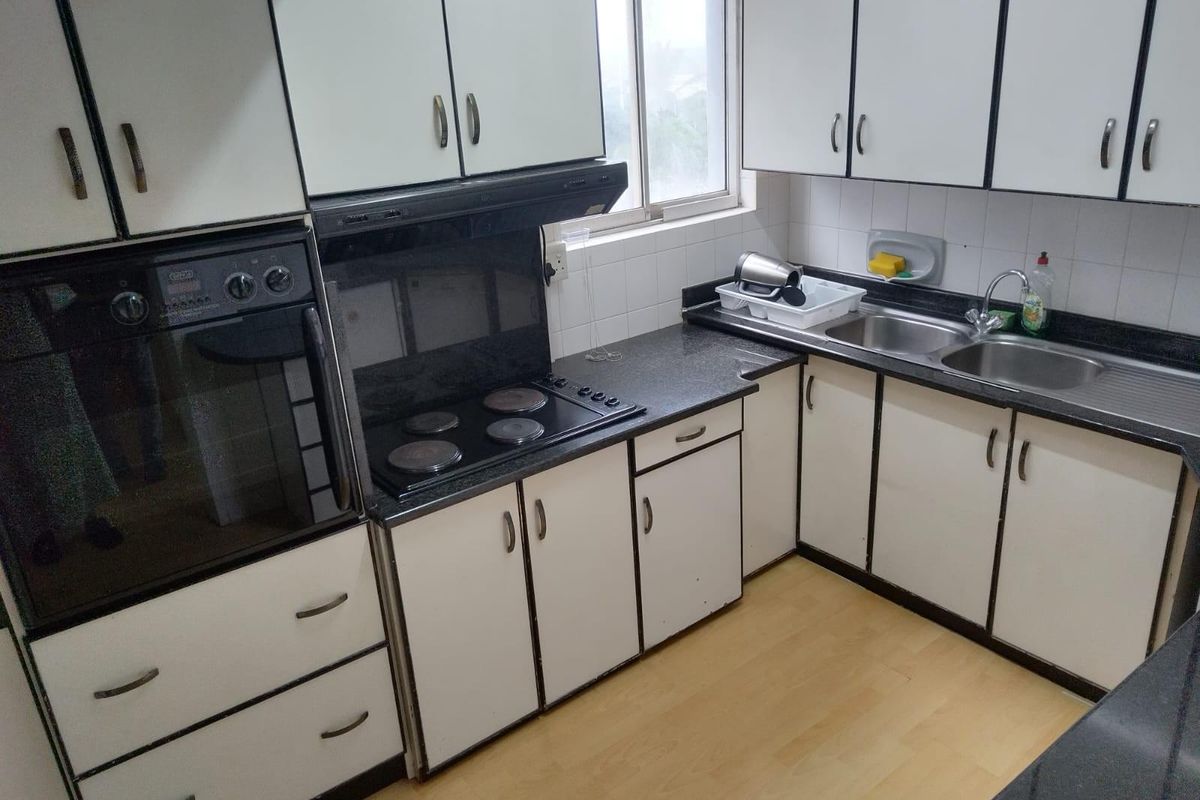 A functional kitchen featuring built-in oven, electric hob, extractor fan, double basin sink, and granite countertops with ample cabinetry storage.