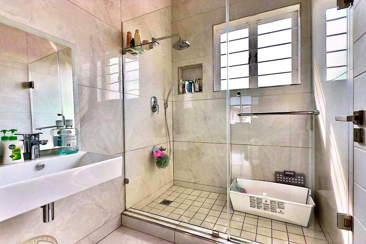 Modern bathroom featuring floor-to-ceiling marble-look wall tiles, a glass-enclosed walk-in shower with a built-in niche, and a wall-mounted basin.