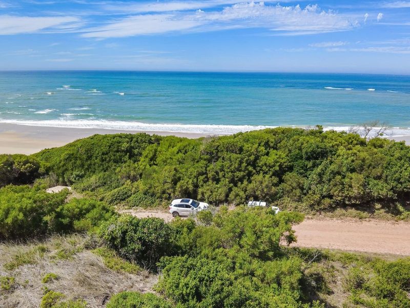 Aerial view of a vacant residential plot featuring natural coastal vegetation and direct proximity to the ocean shoreline.