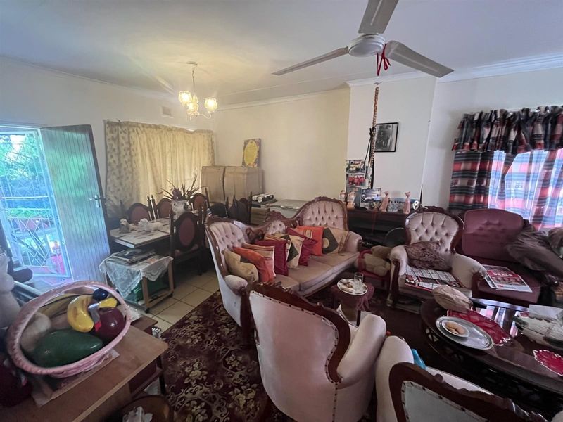 A living room area featuring a ceiling fan, tiled flooring, and access to an outdoor patio space.