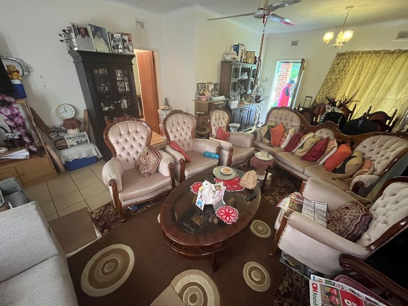 A spacious living room featuring tiled flooring, a ceiling fan, and direct access to the exterior through a glass-paneled door.
