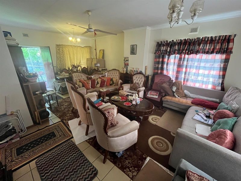 A spacious living room featuring tiled flooring, a ceiling fan, and large windows, providing a comfortable and functional area for relaxation.