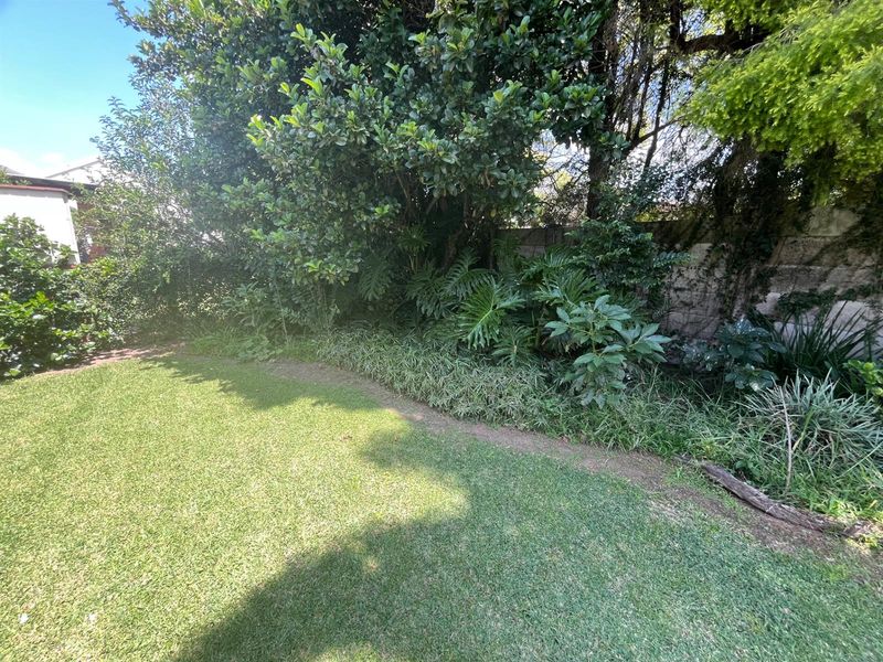 A private garden area featuring a well-maintained lawn and established perimeter landscaping with mature trees and shrubs.