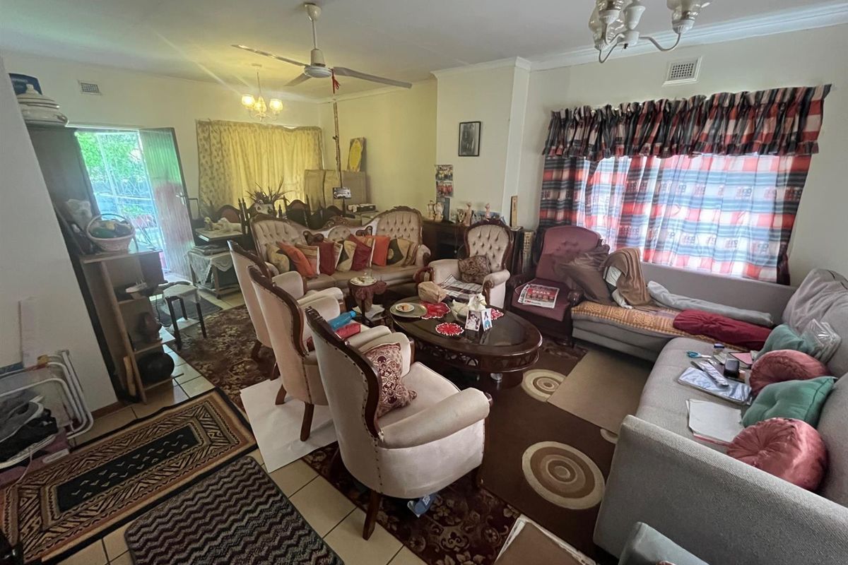 A spacious living room featuring tiled flooring, a ceiling fan, and large windows, providing a comfortable and functional area for relaxation.