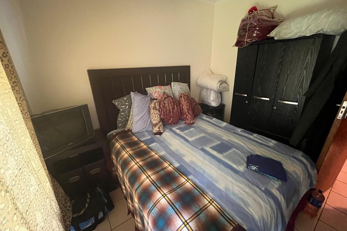 A compact bedroom featuring tiled flooring and neutral wall finishes, providing a functional space for rest.