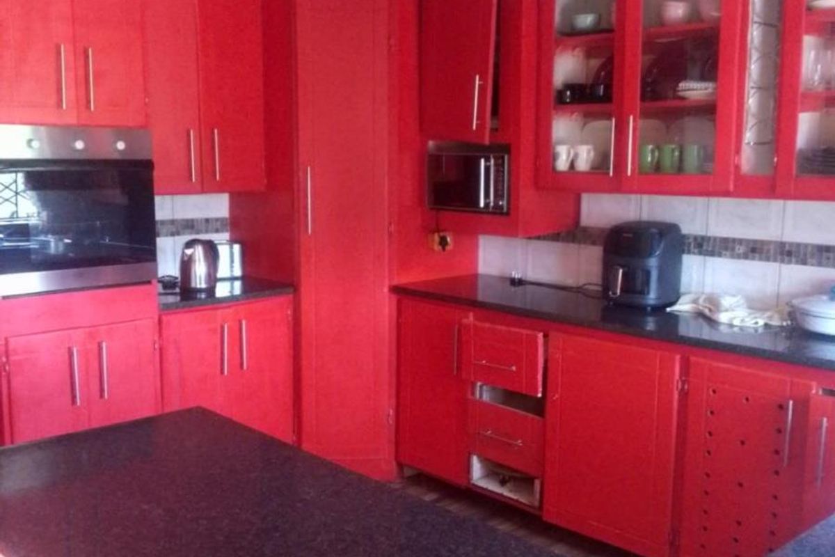 A kitchen featuring bold red cabinetry, dark granite countertops, a built-in oven, and a central island, requiring minor repairs to cabinetry.