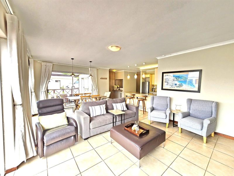 Open-plan living and dining area featuring tiled flooring, a breakfast bar, and seamless flow to an outdoor patio space.