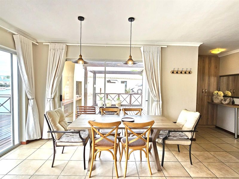 Bright dining area featuring tiled flooring, dual pendant lighting, and large sliding glass doors providing seamless access to the outdoor patio space.