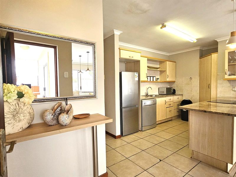 A functional kitchen featuring light wood cabinetry, granite countertops, tiled flooring, and an integrated breakfast nook, offering a practical layout for daily meal preparation.