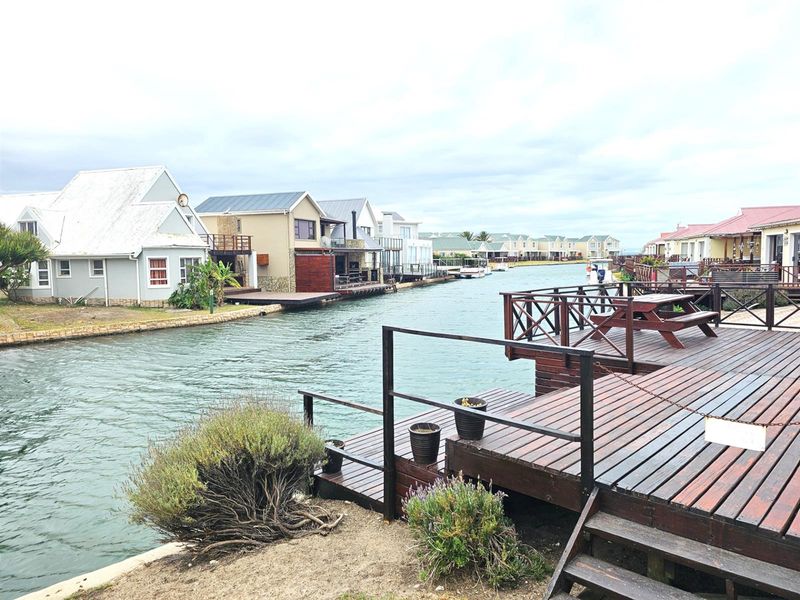 A scenic view of a canal-side property featuring a private timber deck and direct water access within a residential estate.