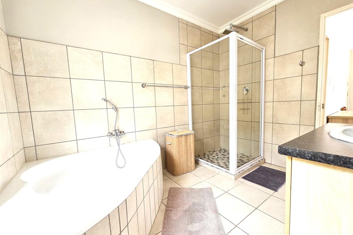 A functional bathroom featuring a corner bathtub, a separate glass-enclosed shower, and a vanity unit with a countertop basin.