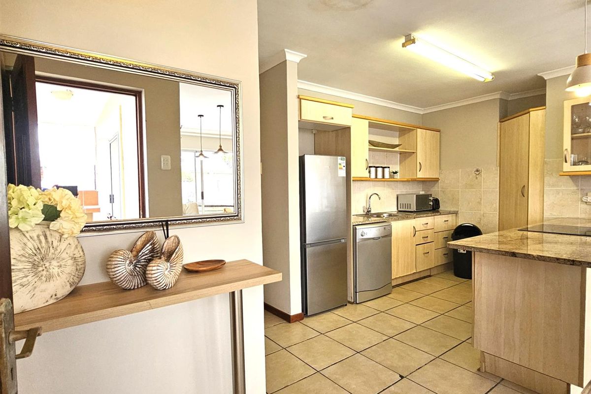 A functional kitchen featuring light wood cabinetry, granite countertops, tiled flooring, and an integrated breakfast nook, offering a practical layout for daily meal preparation.
