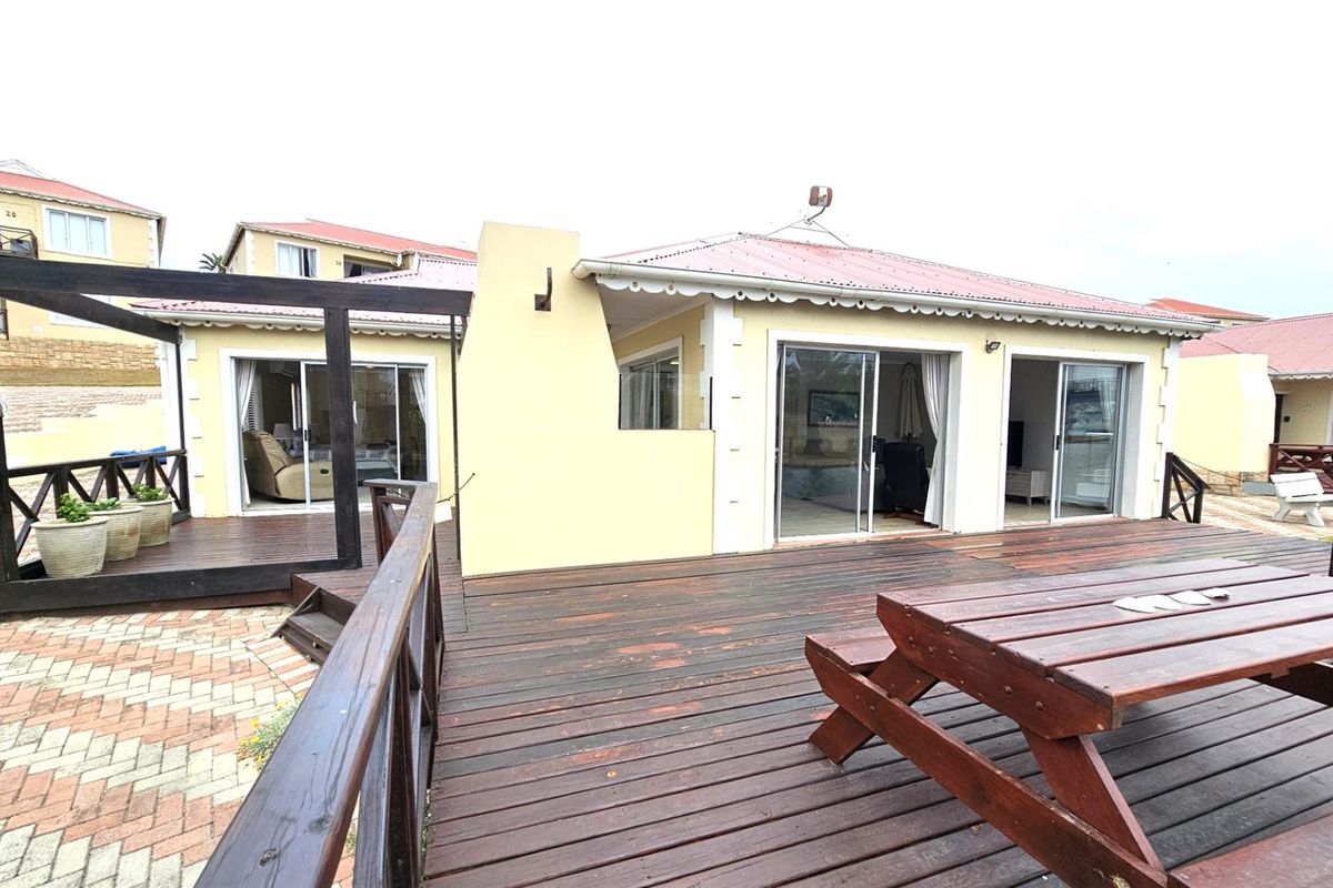 A spacious rear timber deck featuring a built-in outdoor fireplace, providing direct access to the living areas through sliding glass doors.