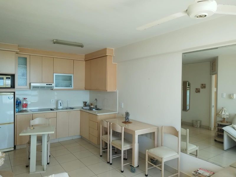 Open-plan kitchen and dining area featuring light wood-tone cabinetry, tiled flooring, and a built-in extractor fan.