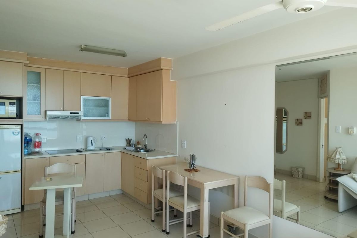 Open-plan kitchen and dining area featuring light wood-tone cabinetry, tiled flooring, and a built-in extractor fan.