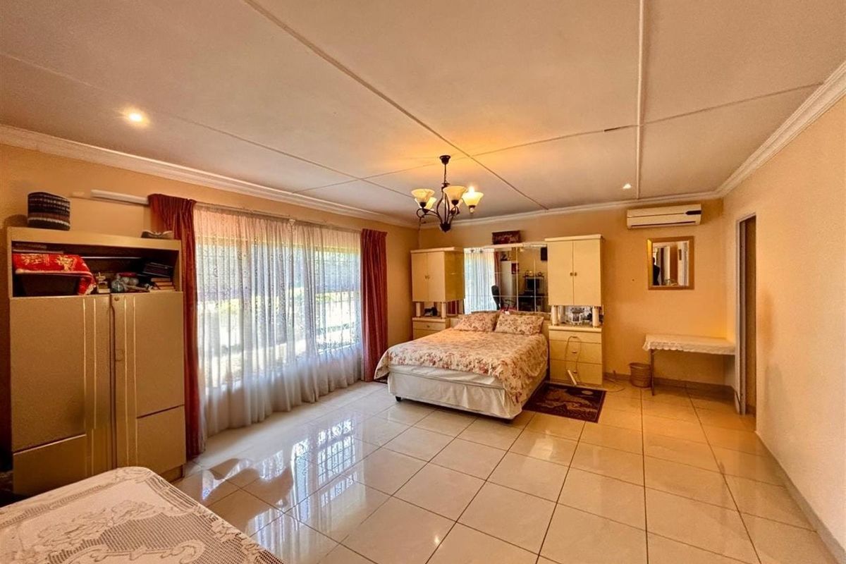 Spacious bedroom featuring large format floor tiles, built-in cabinetry, and a wall-mounted air conditioning unit.