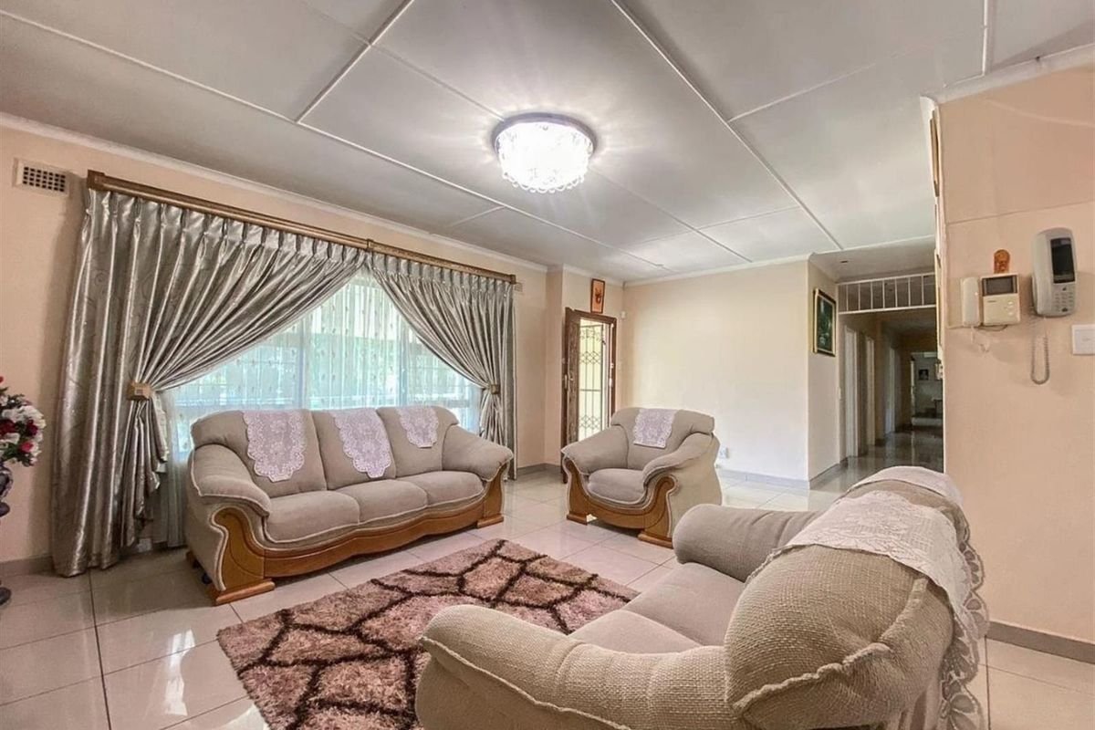 A spacious living room featuring tiled flooring, a flush-mount ceiling light, and a hallway leading to the rest of the home.