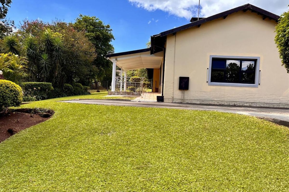 Side view of the house featuring a covered patio area, well-maintained lawn, and established garden landscaping.