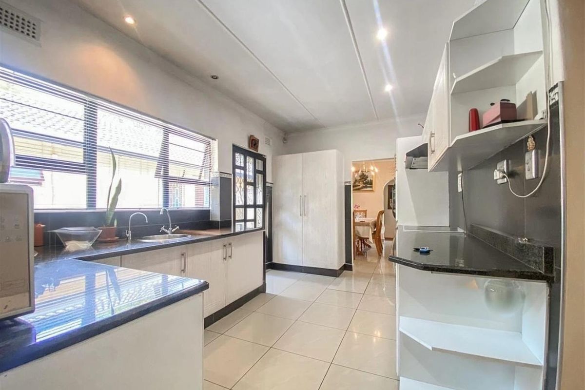 A functional kitchen featuring white cabinetry, dark granite countertops, tiled flooring, and recessed ceiling lighting, offering a clean and practical workspace.
