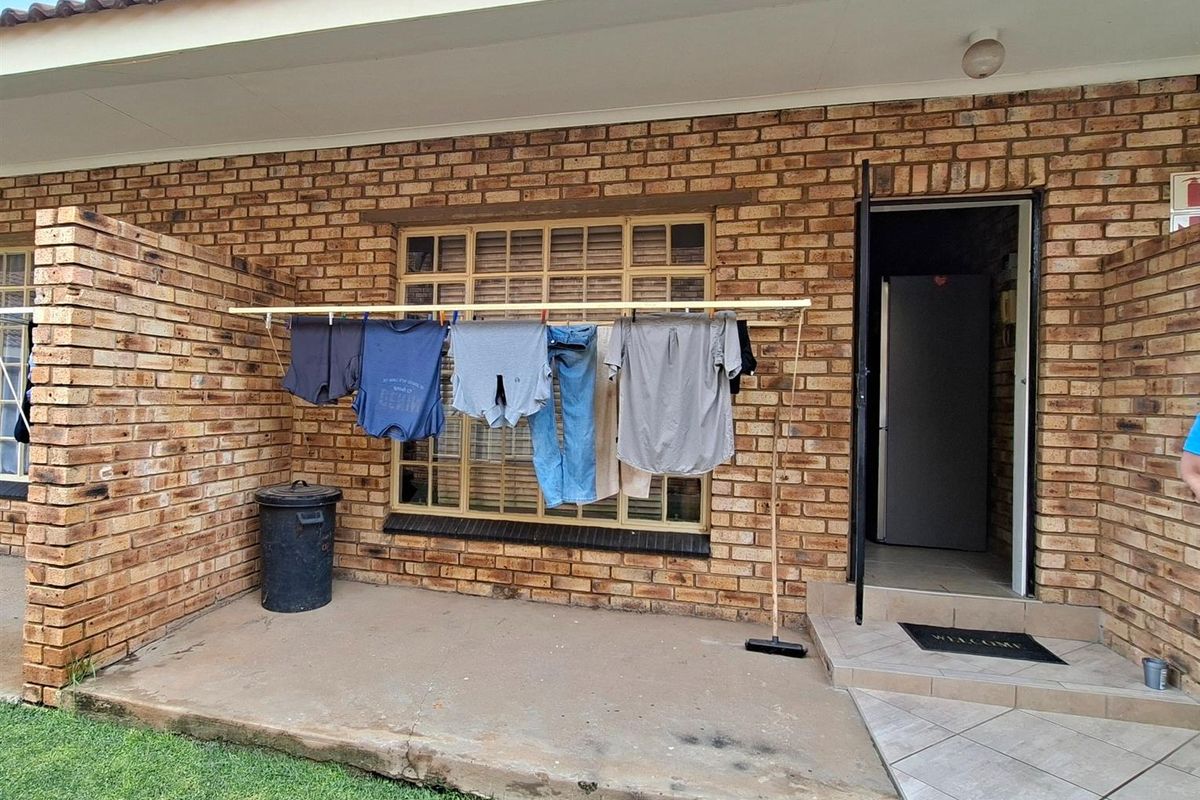 A rear patio area featuring exposed brick walls, a concrete floor, and a tiled entrance step leading into the apartment.
