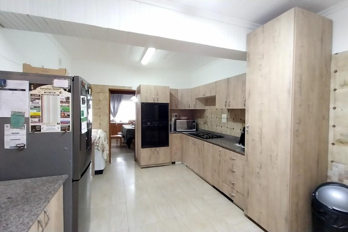 A functional kitchen featuring light wood-tone cabinetry, built-in oven, gas hob, and tiled splashbacks with neutral floor tiles.
