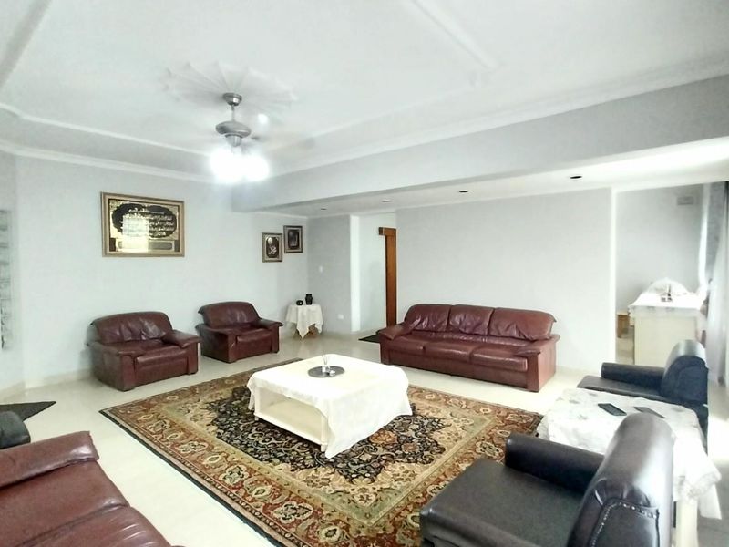 Spacious living room featuring a decorative ceiling rose, recessed lighting, and a ceiling fan, providing a comfortable and well-lit area for relaxation.