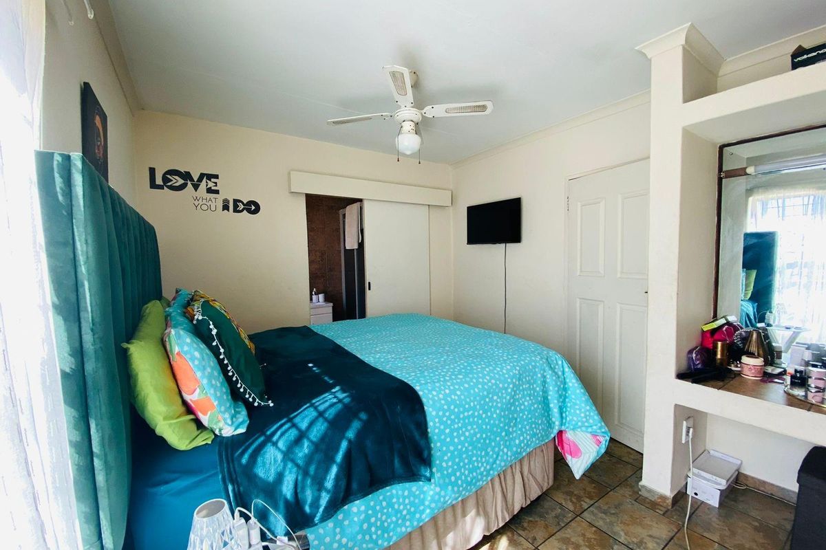 A bedroom featuring a ceiling fan, built-in vanity area, and tiled flooring, providing a functional space with direct access to an en-suite bathroom.