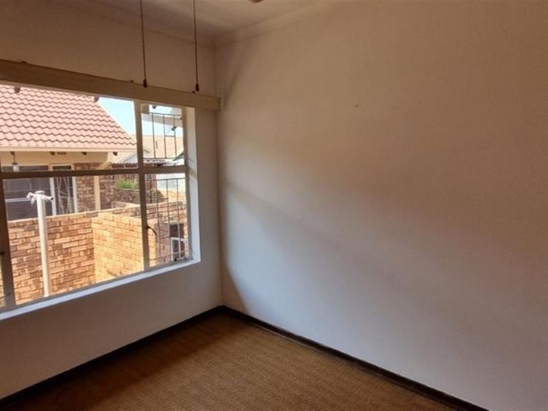 A vacant bedroom featuring a large window providing natural light and carpeted flooring, ready for personalization.