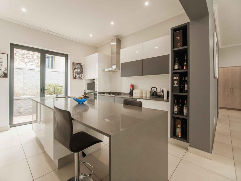Modern kitchen featuring a central island with stone countertops, sleek cabinetry, built-in appliances, and recessed lighting, offering a clean and contemporary aesthetic.