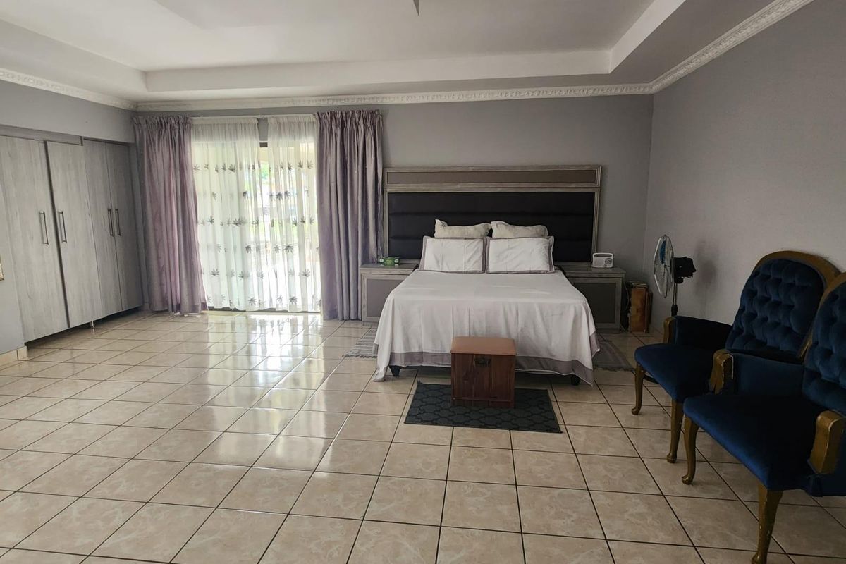 Spacious bedroom featuring tiled flooring, built-in cupboards, and sliding glass doors providing access to the exterior.