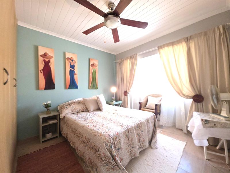A cozy bedroom featuring a tongue and groove ceiling, a ceiling fan, and built-in wardrobe storage.