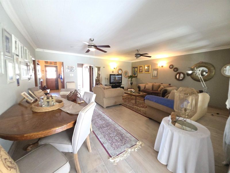Spacious open-plan living and dining area featuring tiled flooring, ceiling fans, and wall sconce lighting, providing a comfortable and functional layout.