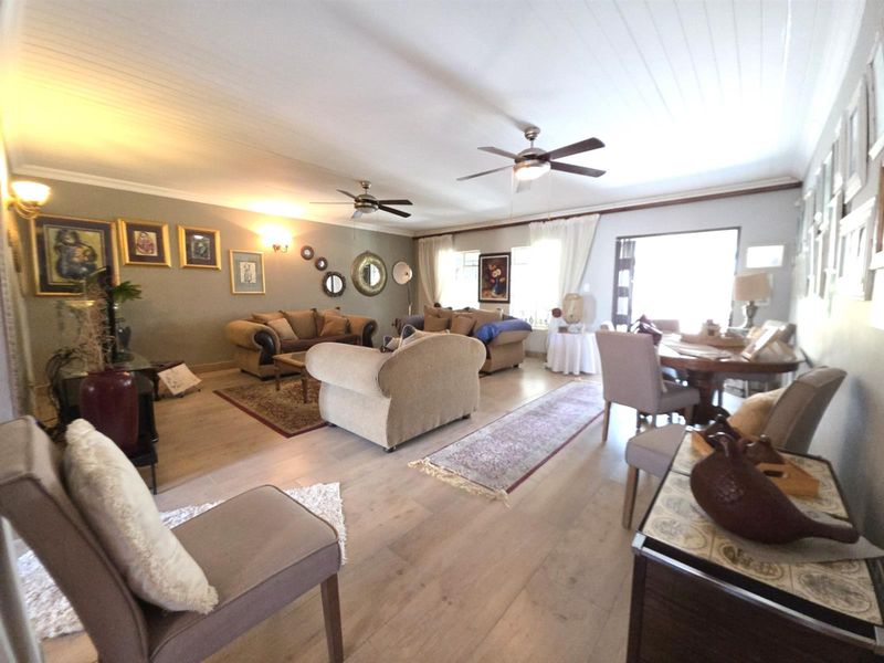 Spacious open-plan living and dining area featuring laminate flooring, ceiling fans, and a classic tongue and groove ceiling finish.