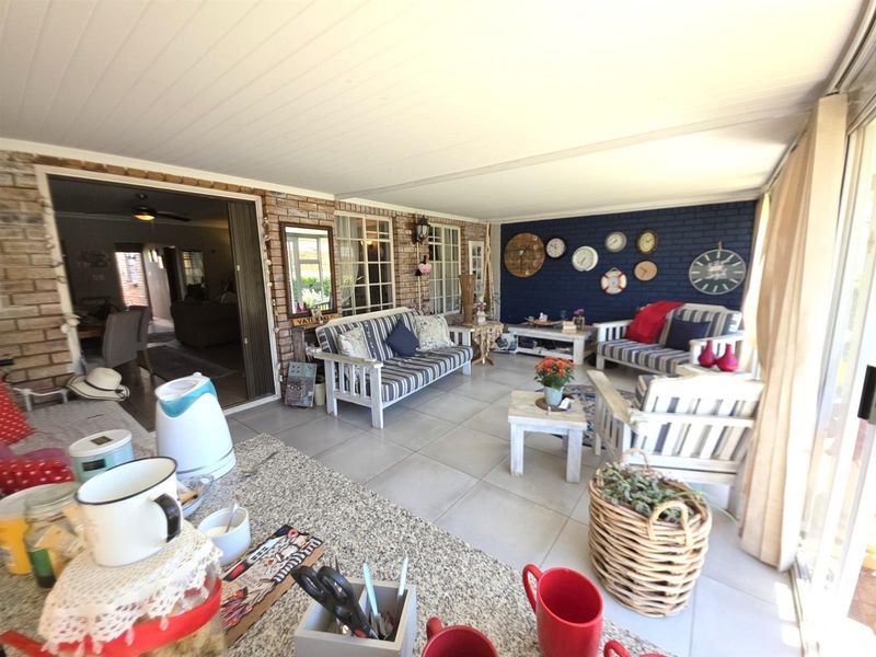 A spacious covered patio featuring tiled flooring, exposed brickwork, and a painted feature wall, providing a comfortable transition between indoor and outdoor living areas.