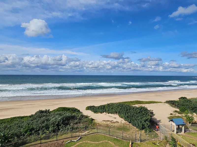 A scenic elevated view overlooking the sandy beach and ocean coastline, showcasing the natural coastal landscape.