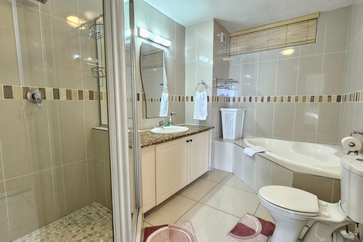 A functional bathroom featuring a glass-enclosed shower, a built-in bathtub, and a vanity with a granite countertop.