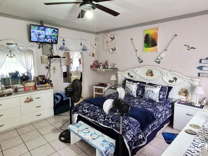 A bedroom featuring tiled flooring and a ceiling fan, offering a functional space with potential for modern updates.