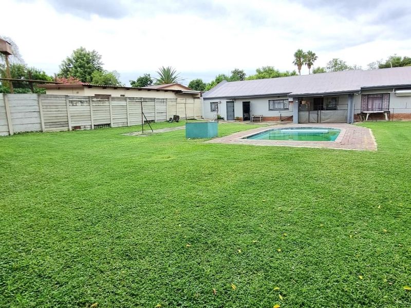 Spacious rear garden featuring a swimming pool with brick paving, enclosed by a precast concrete boundary wall.