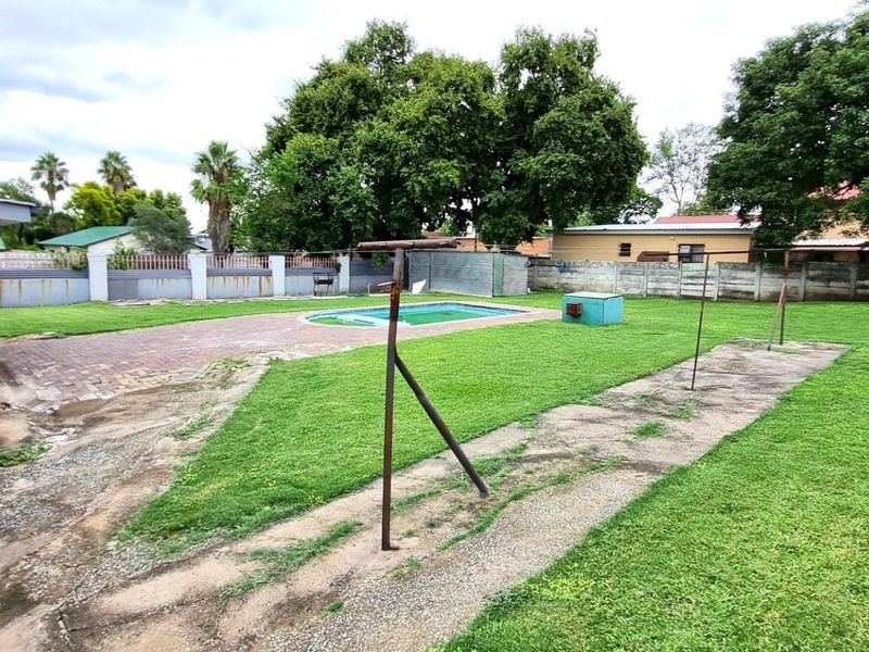 Spacious rear garden featuring a swimming pool, paved patio area, and perimeter walling, offering potential for landscaping and outdoor entertainment upgrades.