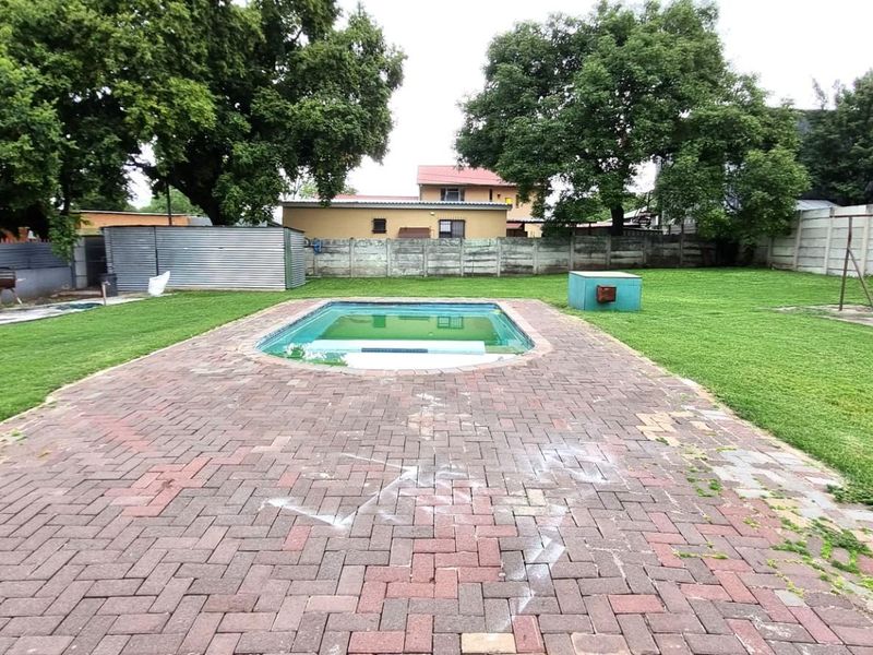 Spacious backyard featuring a swimming pool, paved patio area, and established lawn, enclosed by precast concrete boundary walls.