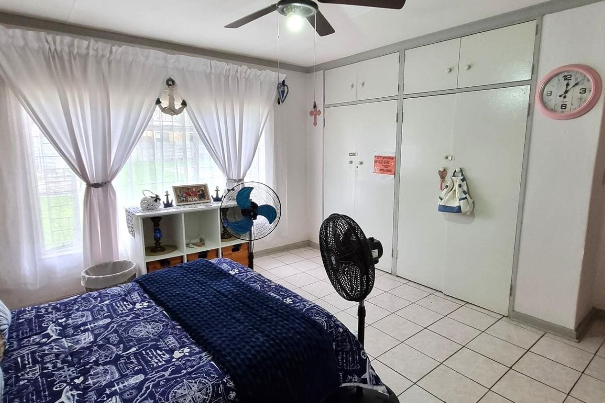 A functional bedroom featuring tiled flooring, a ceiling fan, and ample built-in cupboard storage space.
