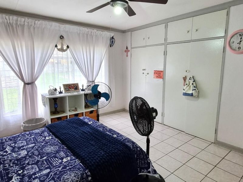 A functional bedroom featuring tiled flooring, a ceiling fan, and ample built-in cupboard storage space.
