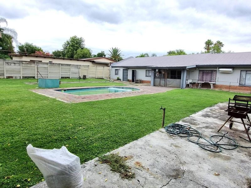 Spacious rear garden featuring a swimming pool, paved patio area, and perimeter boundary walling.