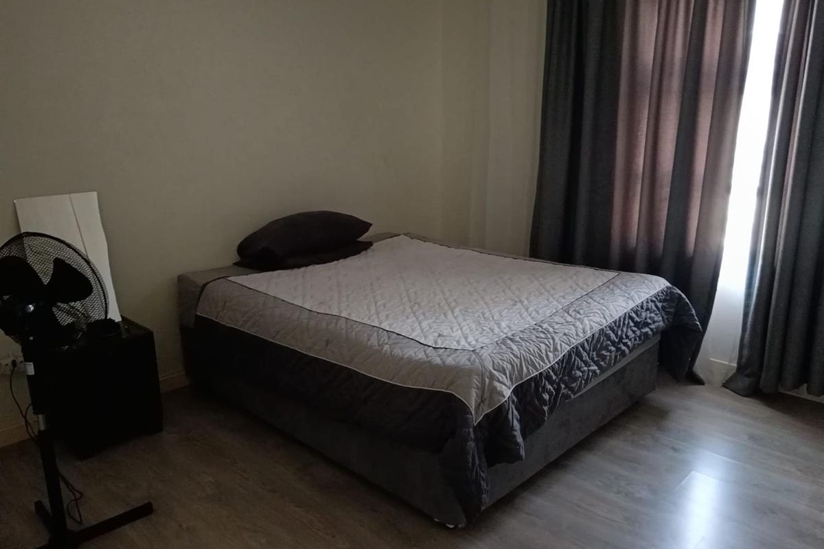 A bedroom featuring wood-look laminate flooring and floor-to-ceiling curtains.