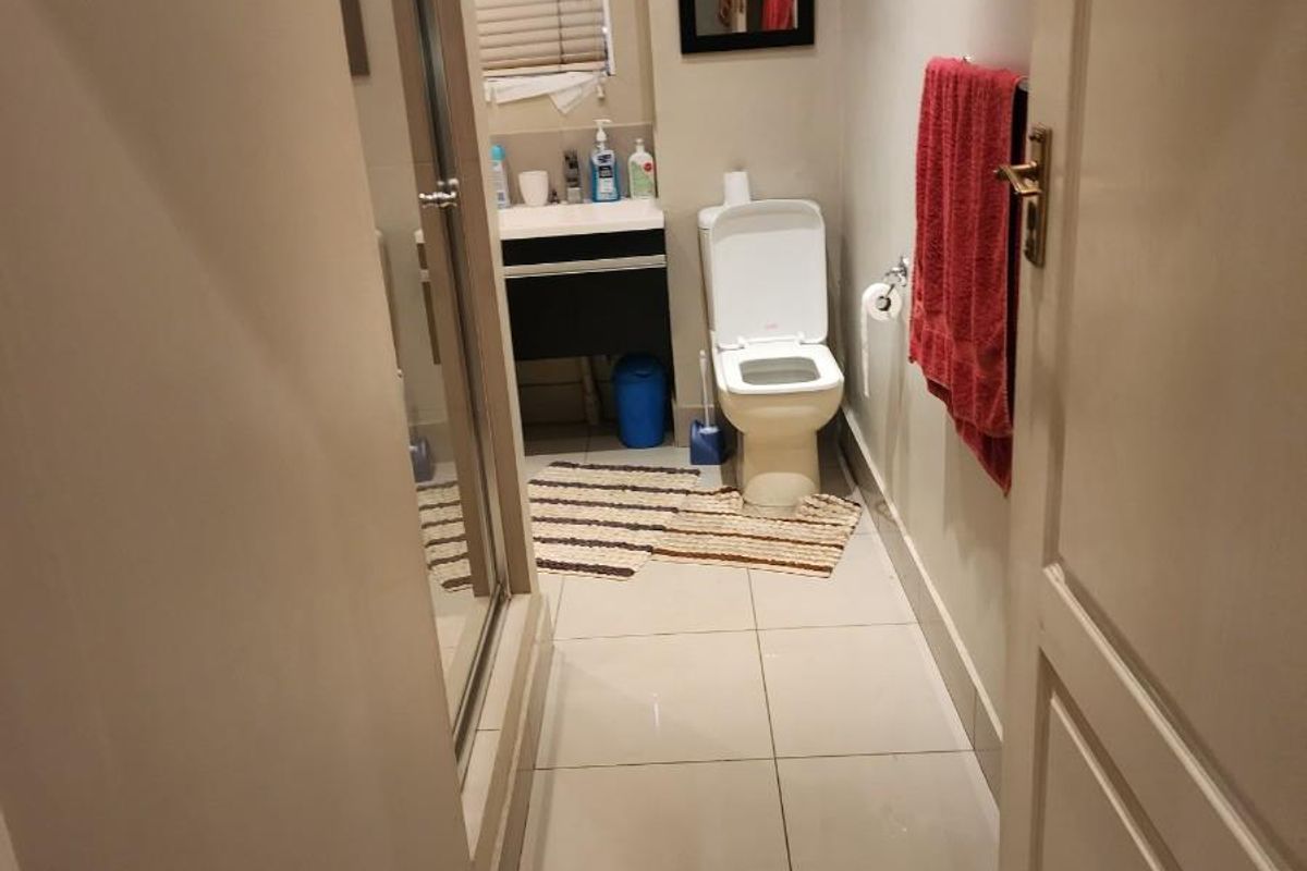 A functional bathroom featuring a glass-enclosed shower, a modern vanity unit, and tiled flooring, providing a clean and practical space.
