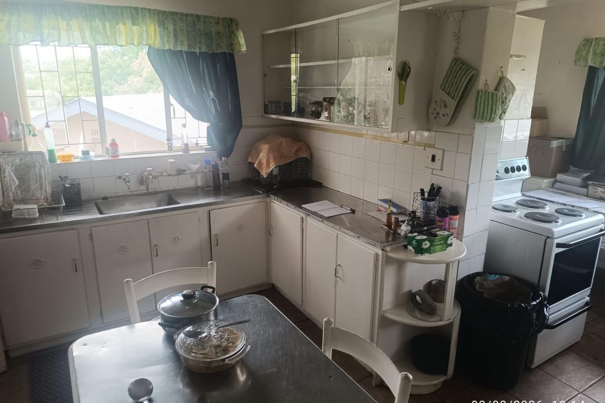 A functional kitchen featuring built-in cabinetry, a stainless steel sink, and tiled backsplash, offering potential for modernization and aesthetic updates.