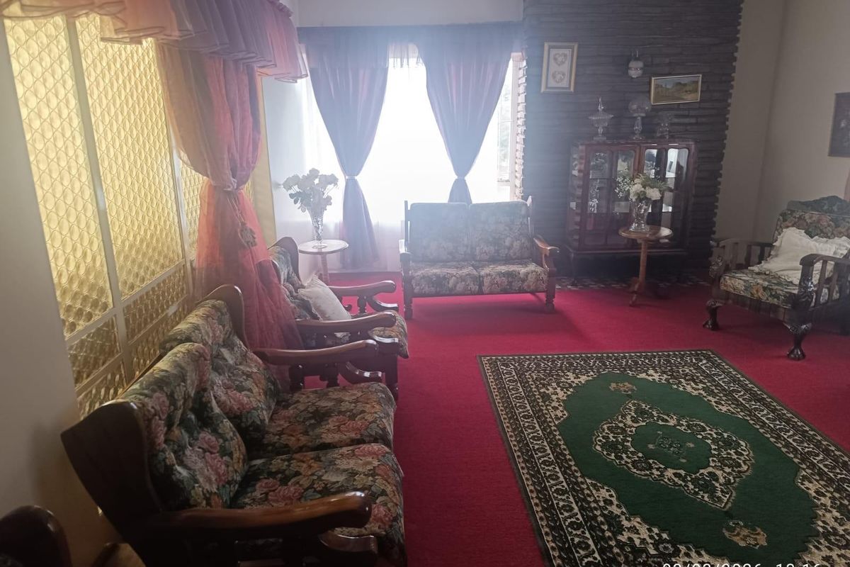 A traditional living room featuring a prominent brick fireplace and a decorative room divider, offering a classic layout with potential for modernization.