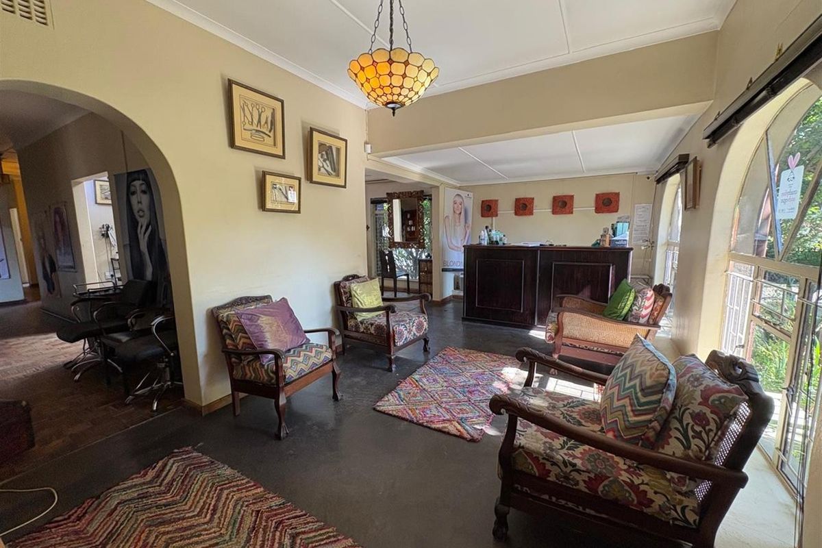 A spacious reception area featuring arched entryways, large windows, and a built-in service counter, currently utilized as a commercial salon space.